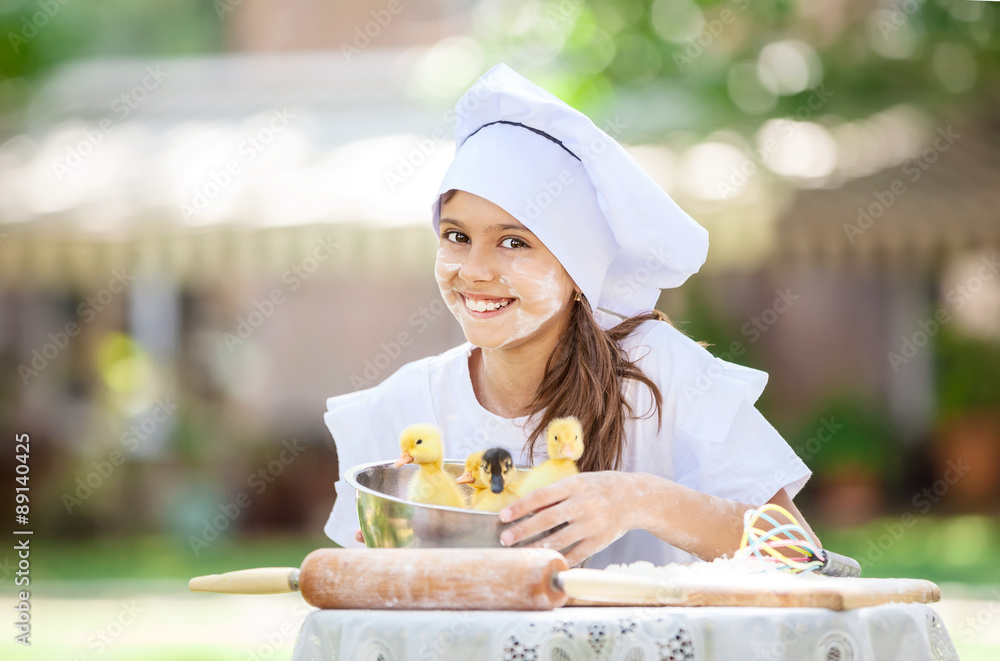 Smiling little chef showing ducklings in a bowl while cooking outdoors Smiling little chef showing ducklings in a bowl while cooking outdoors