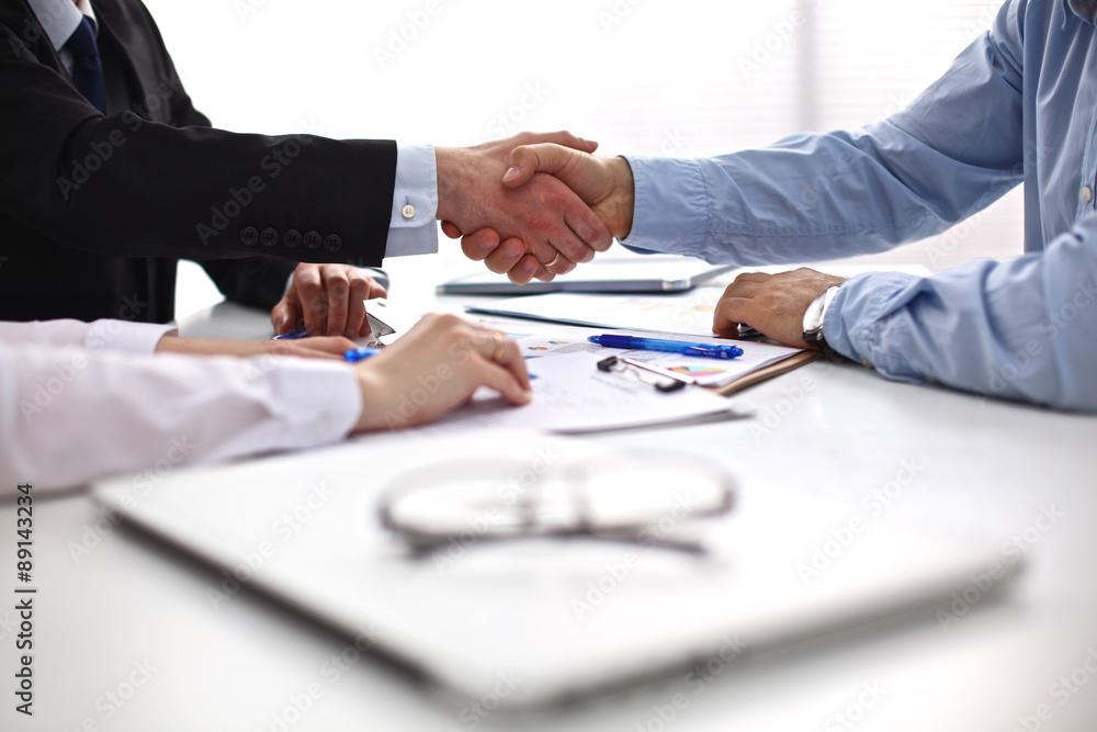 Business meeting at the table shaking hands conclusion of the Business meeting at the table shaking hands conclusion of the