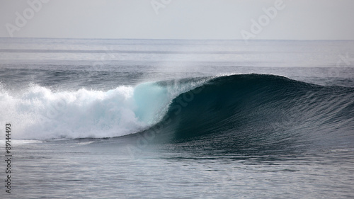 A wave breaks unridden on a shallow coral reef in the Mentawai Islands - Indonesia photo
