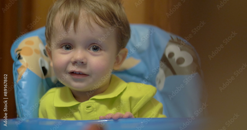 Lovely smiling boy sitting at feeding table Lovely smiling boy sitting at feeding table