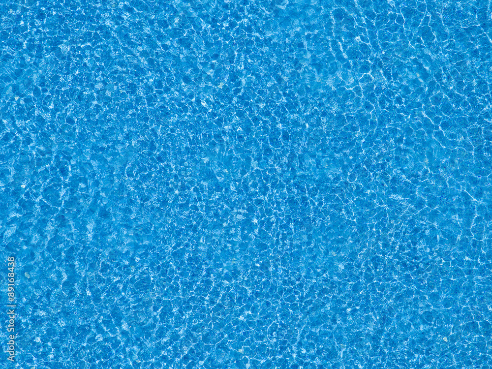 Water ripples on blue tiled swimming pool background.