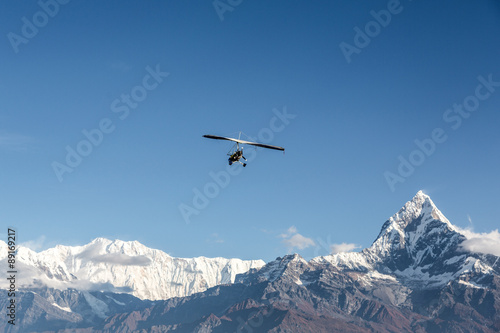 Ultra light plane flying over the Annapurna mountain range in the Himalayas near Pokhara, Nepal. The summit on the right is the Machapuchare (6993m), aka the fishtail mountain.