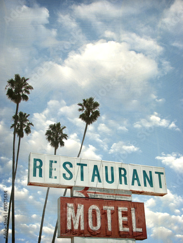 aged and worn vintage photo of motel and restaurant neon sign with palm trees
