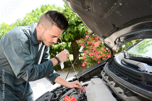 handsome young man car mechanic checking a car engine breakdown outdoor