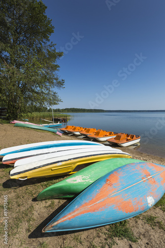 Fototapeta Naklejka Na Ścianę i Meble -  Colorful kayaks moored on lakeshore, Goldopiwo Lake, Mazury, Pol