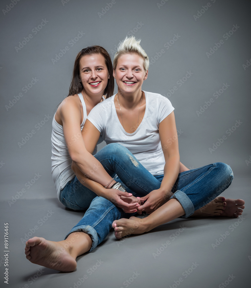 Two young cheerful sister hugging in the studio. Two young cheerful sister hugging in the studio.