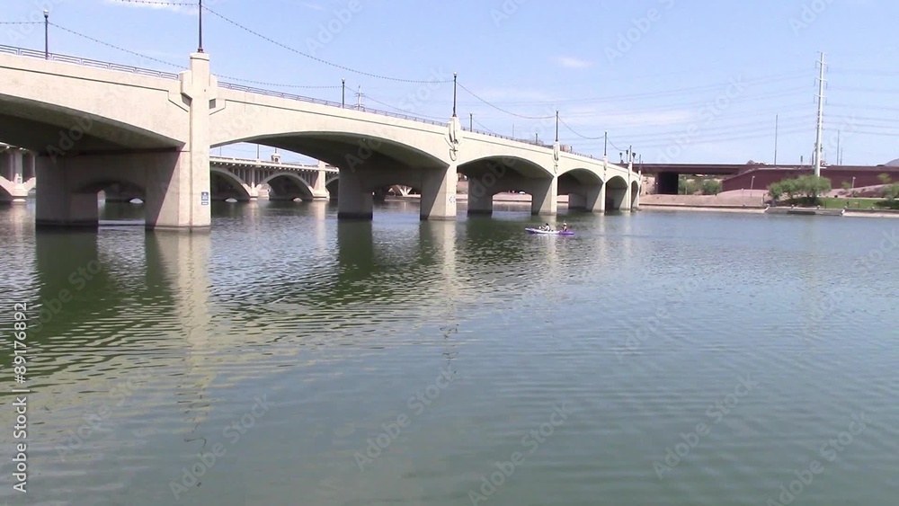 Kayak passing under bridge on lake. Kayak passing under bridge on lake.