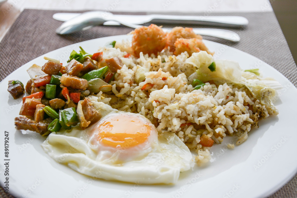 Chinese fried rice with vegetables, chicken and fried eggs served on a plate with chopsticks