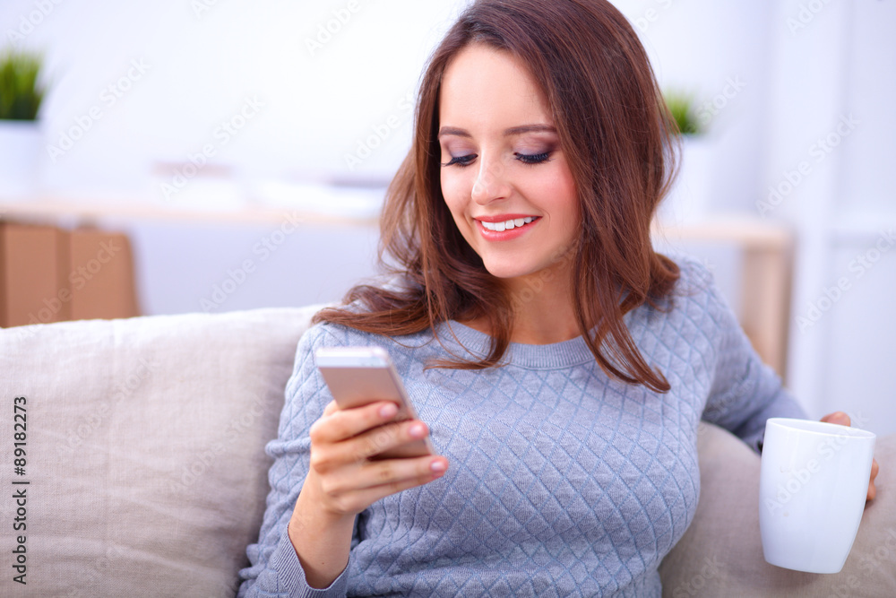 Pretty girl using her smartphone on couch at home in the living Pretty girl using her smartphone on couch at home in the living