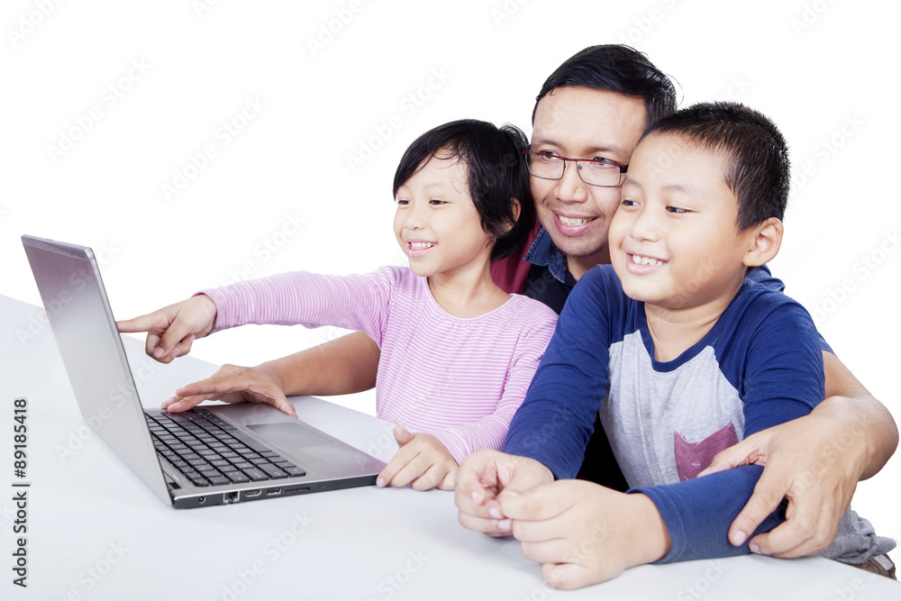 Kids using laptop on the table with their father Kids using laptop on the table with their father