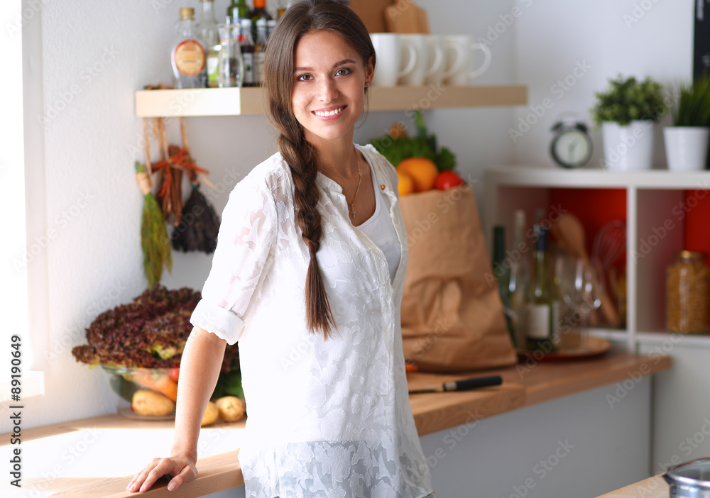 Young woman standing near desk in the kitchen Young woman standing near desk in the kitchen