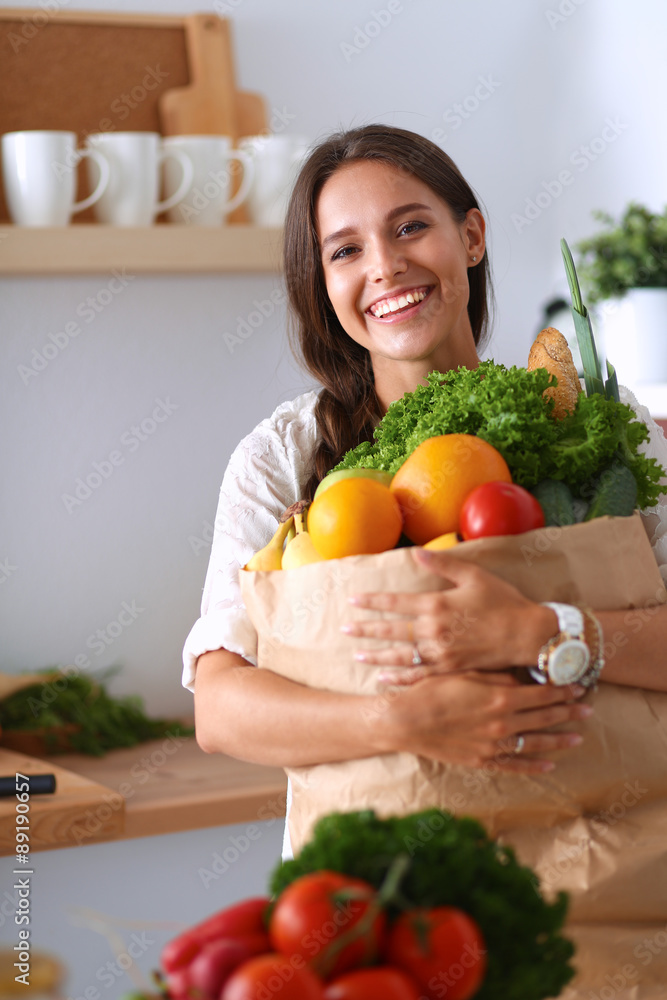 Young woman holding grocery shopping bag with vegetables 