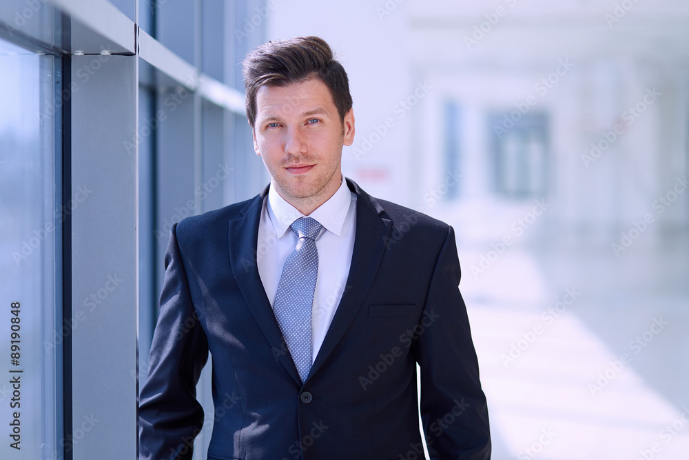 Portrait of businessman standing near window in office Portrait of businessman standing near window in office