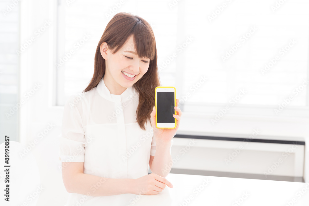 部屋でスマホの画面を見せる女性 部屋でスマホの画面を見せる女性