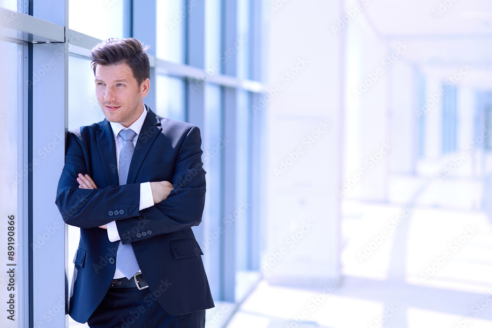Portrait of businessman standing near window in office Portrait of businessman standing near window in office