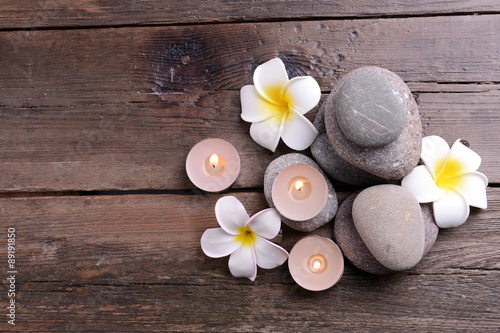 Beautiful spa composition with candles and flowers on wooden table close up