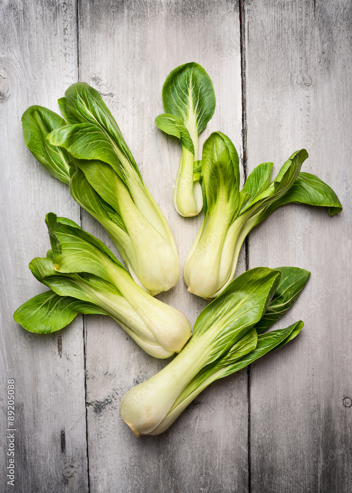 new baby pak choi on white wooden background new baby pak choi on white wooden background