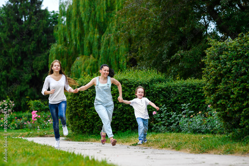 Happy Mother with daughter and son running on grass smiling Happy Mother with daughter and son running on grass smiling