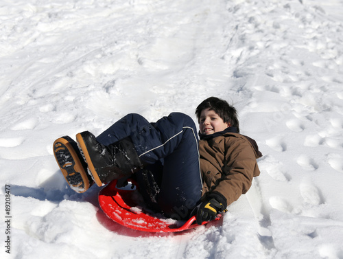 Boy plays with sledging in winter on the white snow