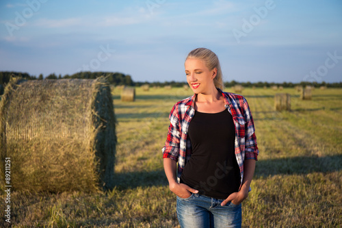 beautiful romantic country girl walking in field with haystacks