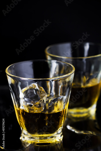 Two glasses of whiskey with ice cubes