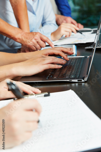 Viele Hände im Büro an Laptop und Tablet Computer