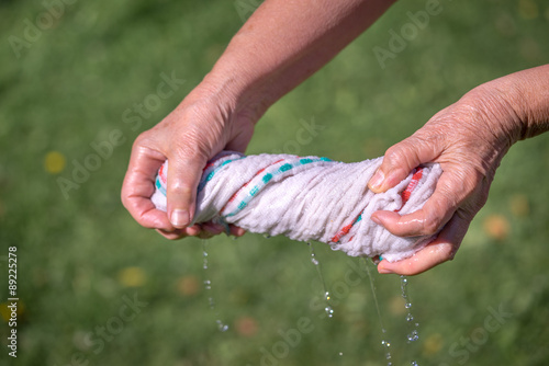 Hands squeeze wet fabric on a grass background © elen31