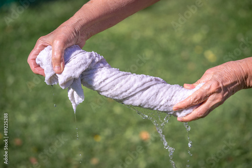 Hands squeeze wet fabric on a grass background © elen31
