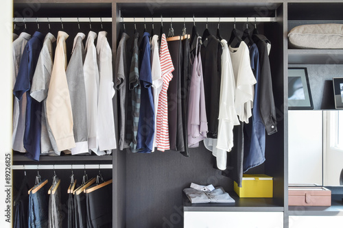 modern closet with row of cloths hanging in black wardrobe photo