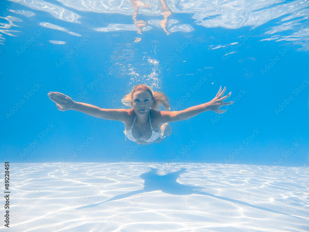A young woman diving in a blue clean water