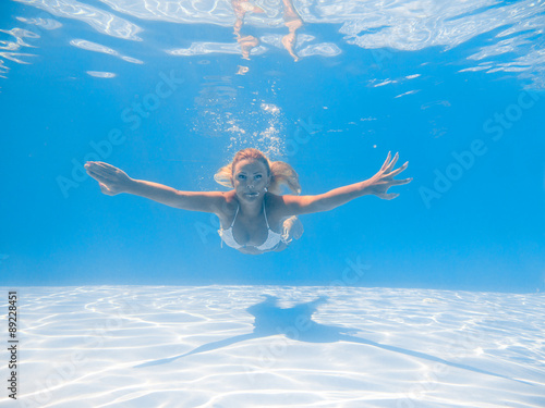 A young woman diving in a blue clean water