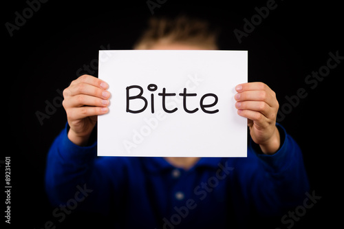 Child holding sign with German word Bitte - Please