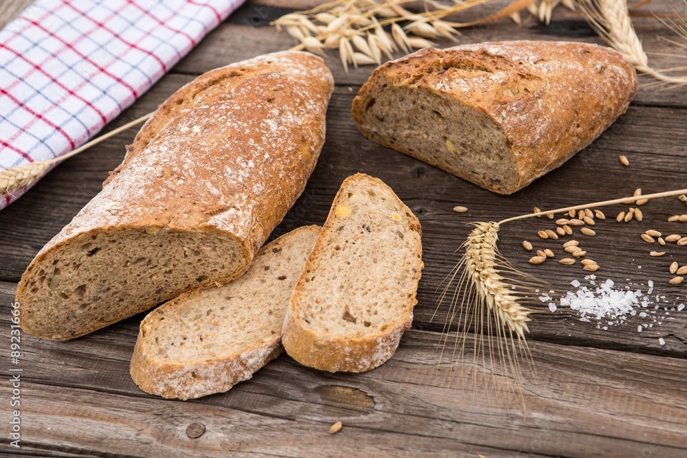 Naklejka premium Rustic bread and wheat on an old vintage planked wood table.