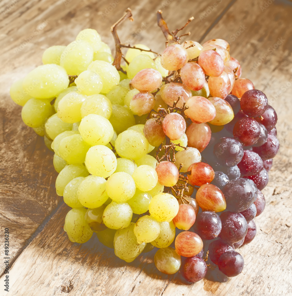 Green, pink and purple grapes on old wooden table, selective foc Green, pink and purple grapes on old wooden table, selective foc