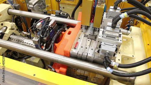 A wider shot cuts to a close-up of an injection molding machine in a factor
 photo