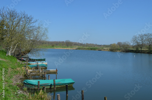 Covered rowing boats docked on a wide river