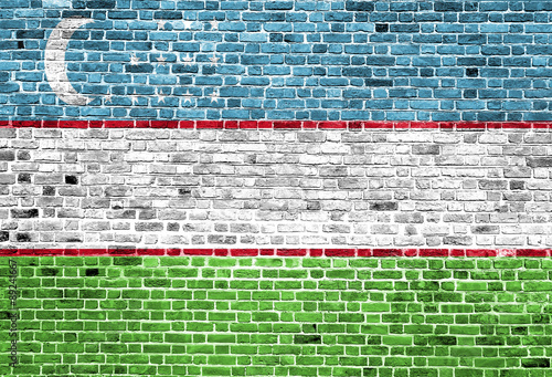 Flag of Uzbekistan painted on brick wall, background texture photo