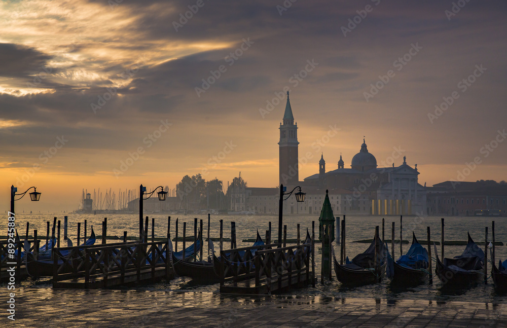 Fototapeta premium Gondolas by Saint Mark square during sunrise with San Giorgio di Maggiore church in the background in Venice Italy