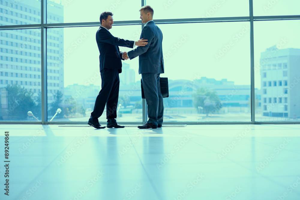 Full length image of two successful business men shaking hands Full length image of two successful business men shaking hands