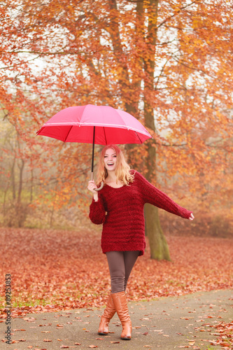 Fashion woman with umbrella relaxing in fall park.