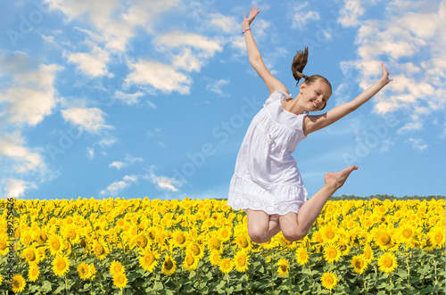 Cheerful girl jumping on a background of sunflowers