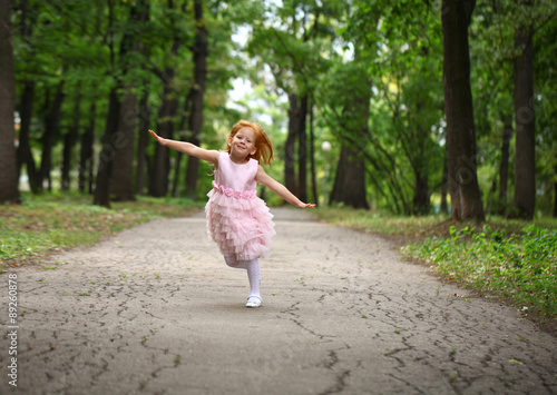 Fototapeta Naklejka Na Ścianę i Meble -  Happy little girl runs in a summer park