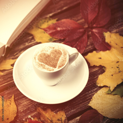 Autumn leafs  book and coffee cup on wooden table.