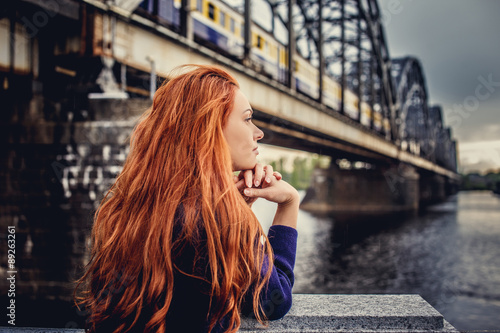 Redhead casual woman posing near big river photo