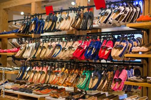 Rows of bright woman shoes on hangers and shelves in store