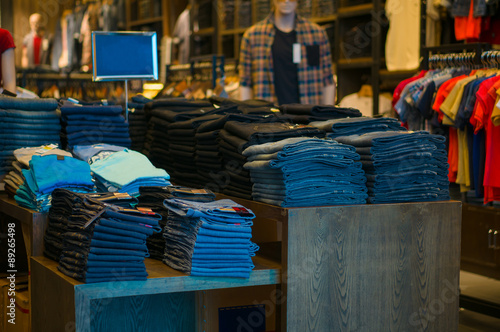 Variety of jeans and shirts on tables in store © Joshhh