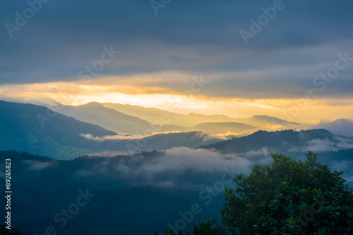 Sun shining through the clouds with silhouetted mountians