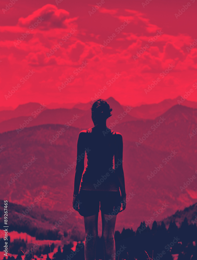 Obraz premium Woman enjoying a dramatic red sunset