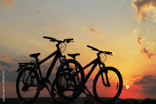 Bikes on top of a car against sunset.