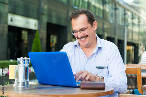 Middle age businessman works on laptop photo